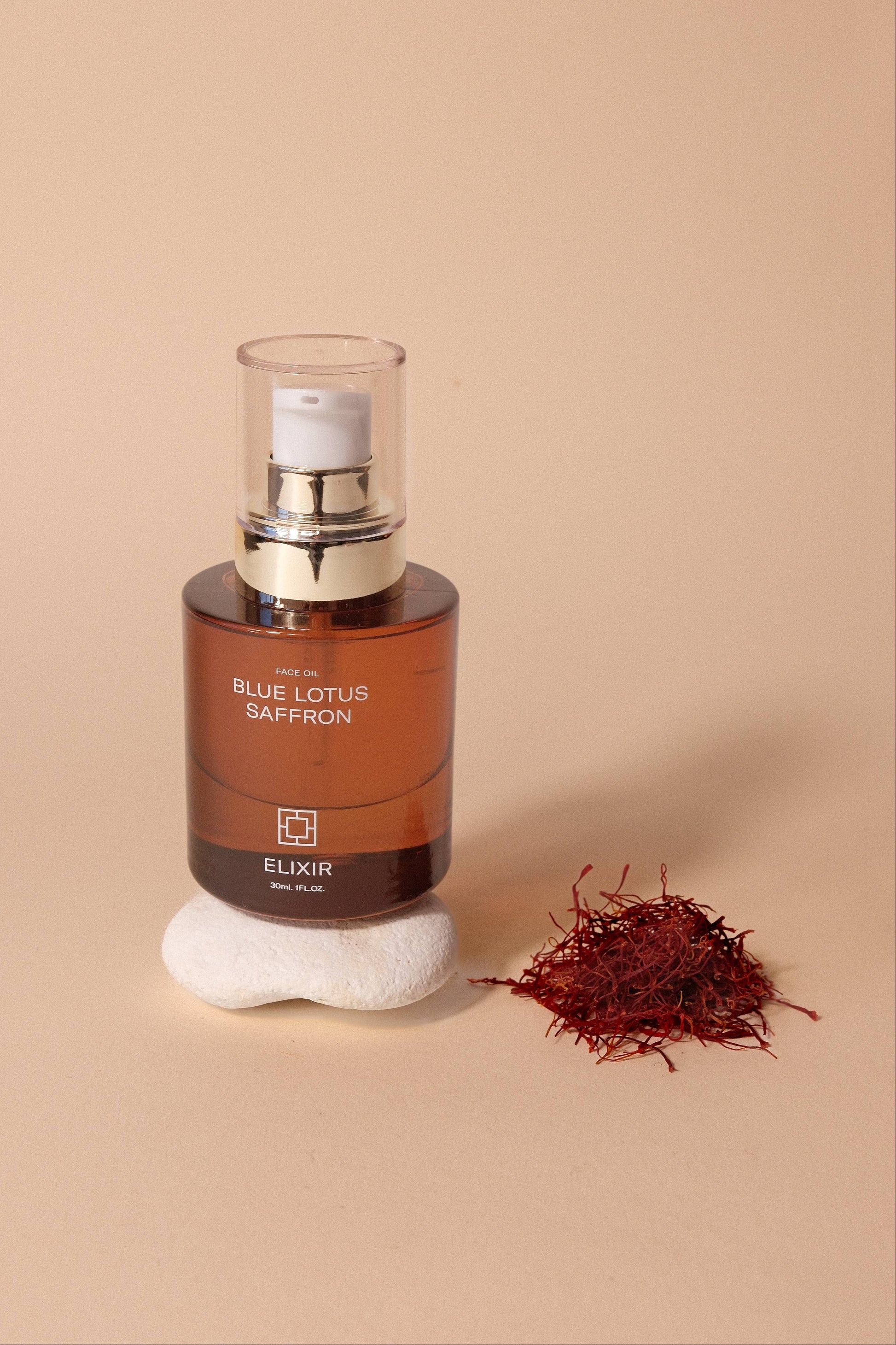 Bottle of 'Blue Lotus Saffron' elixir with saffron strands on a beige background


